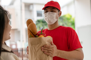 Deliveryman send bags of food to customers in front of the home during the epidemic of Covid-19....