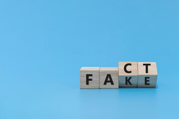 flipping FAKE to FACT word on wooden cube block on blue background, market trend, positive...