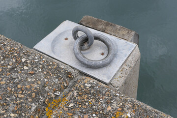 Heavy duty metal ring embedded on dockside with harbour water in background