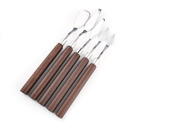 Art palette knives lie on a white art canvas. ainless painting palette knife with wooden handle. Palette knives, isolated on white. set new painting palette knives.