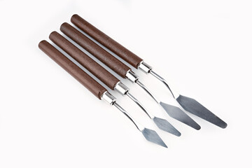 Art palette knives lie on a white art canvas. ainless painting palette knife with wooden handle. Palette knives, isolated on white. set new painting palette knives.