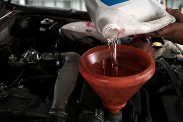 Pouring flushing oil to clean car engine