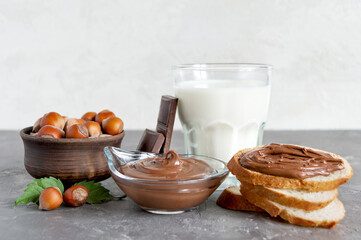 Chocolate nut spread with milk and crispy toasts for breakfast. Composition on the table close-up.