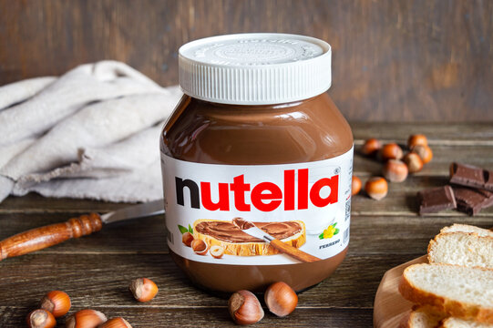 KREMENCHUG, UKRAINE - OCTOBER 9, 2021: Nutella glass jar on a wooden background with freshly baked bread for breakfast. Widely popular brand name by Italian company Ferrero.