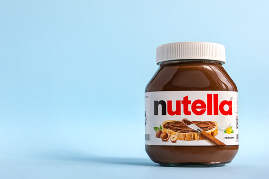 KREMENCHUG, UKRAINE - OCTOBER 9, 2021: Nutella in a glass jar on a blue background. The well-known Ferrero trademark chocolate-nut spread. Copy space