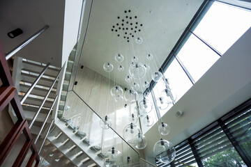 Hanging chandelier with balls in the bright hall with a staircase. High quality photo