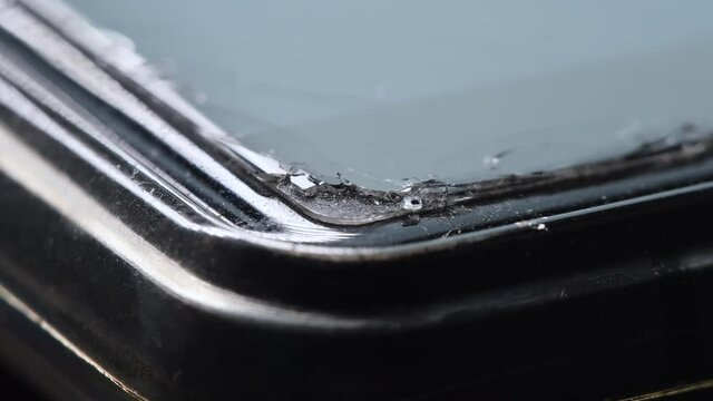 Broken protective glass. Cracked protective film on the screen of a mobile phone. Close-up of the edge of a cell phone in soft focus.