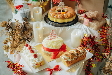Christmas and New Year Gift Cake’s like swiss roll, pudding, tart and snack choco chips with box red ribbon accessories, brown tone warm light