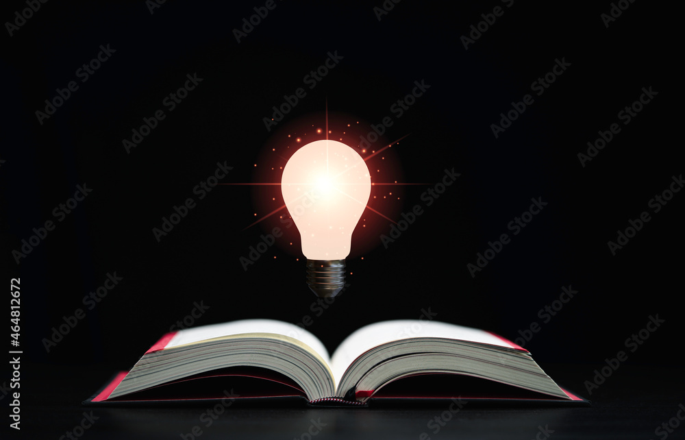 Poster glowing lamp floats above an open book on dark background which is a symbol of study a knowledge wil