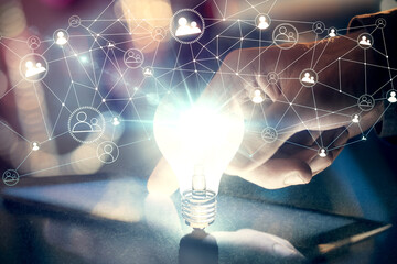 Double exposure of man's hands holding and using a digital device and bulb hologram drawing. Idea concept.