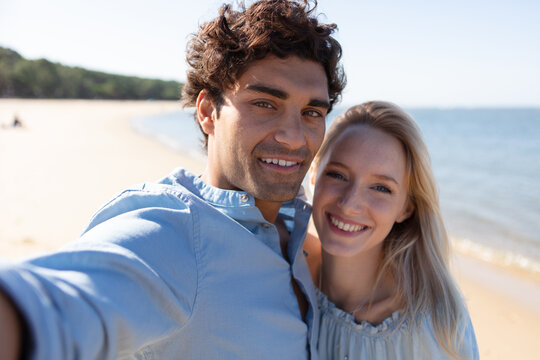 couple relaxing on beach taking selfie picture