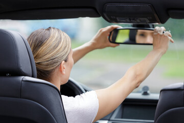 woman adjusting rearview mirror in the car