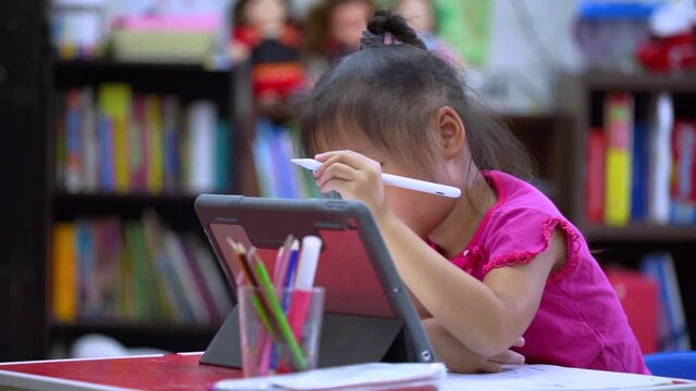 Online education concept. Online class. Asian little girl studying at home. kid in living room at home and using digital tablet to draw.
