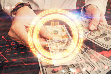 Multi exposure of blockchain theme drawing hologram and USA dollars bills and man hands. Business concept.