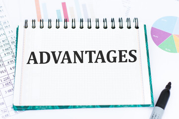 Advantages text on notepad on the background of reports and charts