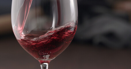 Naklejka na ściany i meble pour red wine into wineglass closeup indoor shot