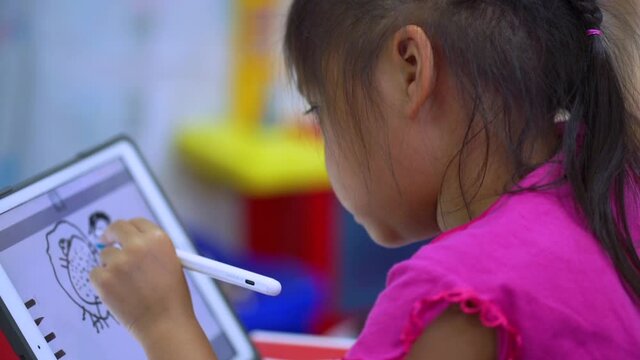 Online education concept. Online class. Asian little girl studying at home. kid in living room at home and using digital tablet to draw.