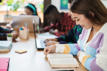 Multiracial students reading books and using laptop while studying together - School concept - Focus on girl eye