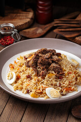 Uzbek national dish pilaf plov with rice and meat on wooden background
