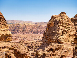 Fototapeta premium Mountain wall of red sand rock that surround the ancient city of Petra, Jordan. Rocky desesrt landscape