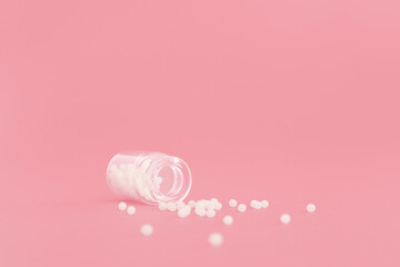 Close-up image of homeopathic globules in glass bottle on pastel pink background. Homeopathy pharmacy, herbal, natural medicine, alternative homeopathy medicine, healthcare. Free space, copy space. - obrazy, fototapety, plakaty