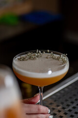 Bartender is preparing a cocktail at the bar. Decoration with flowers ready cocktail in a glass