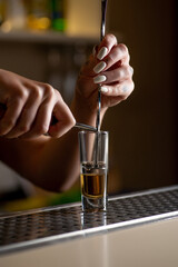 Bartender prepares a multi-layered shot. Barkeeper Female