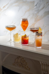 Set of ready-made bright orange cocktails on an antique white fireplace on a marble background