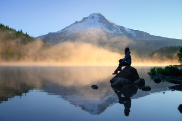 Obraz na płótnie Canvas traveler sitting on rock and looking over scenic Mount Hood view with sunrise at Trillium Lake, Oregon