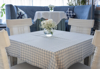 Table setting in restaurant in blue and white colors. Glass vase with white flowers on table in cafe. Creative restaurant decoration. Elegant banquet table. Comfortable cafe furniture.
