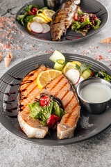 Grilled salmon steak with white sauce and fresh salad