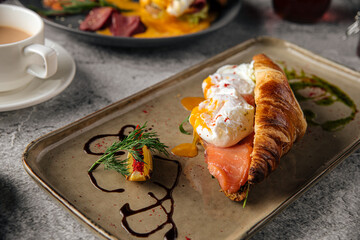 Croissant with poached egg and salmon breakfast on a plate