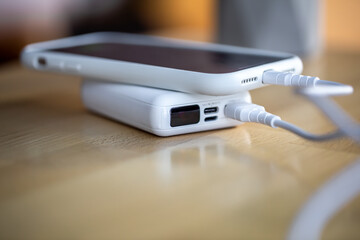 A smartphone is charged from a small white power bank.