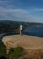 boy on a rock high above watching the sea