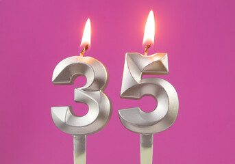 Burning silver birthday candles on pink background, number 35