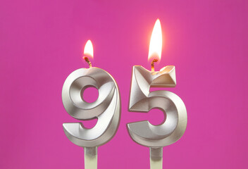 Burning silver birthday candles on pink background, number 95
