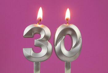 Burning silver birthday candles on pink background, number 30