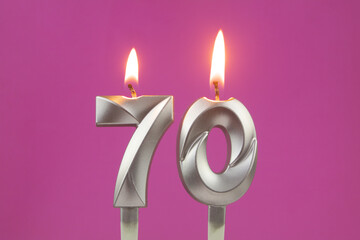 Burning silver birthday candles on pink background, number 70