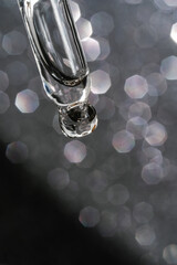 Cosmetic pipette with a drop on dark background.