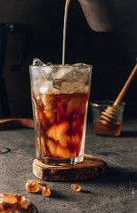 Iced coffee in a tall glass. Dark mood background. Selective focus