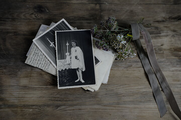 stack of retro monochrome photographs of 50-60s on natural wooden table, photo of child, dried flowers, concept of family tree, genealogy, connection with ancestors, memories of youth, childhood