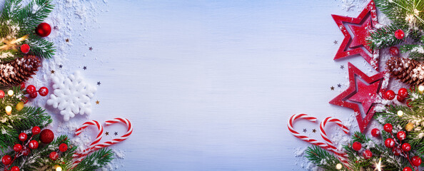 Christmas banner or card with wooden stars, snowy fir tree branches, cones and holiday decorations.