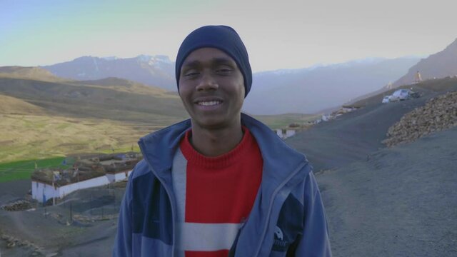 close up shot of a happy young Indian Asian Man standing on a construction site looking towards camera with beautiful landscape view of mountainous region in the background of Northern state of India
