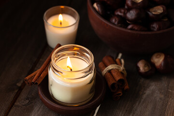 Composition with aromatic candles, cinnamon, chestnut. Cozy home atmosphere, aromatherapy. Dark wooden background