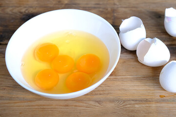 raw chicken eggs in a white cup on the table, broken shells, the concept of cooking scrambled eggs, omelet, home cooking