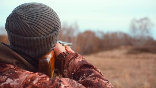 The hunter takes aim with a shotgun. Back view