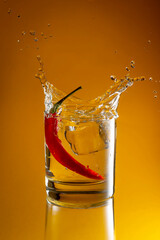Chilli pepper liquor in a glass with ice on yellow blackground