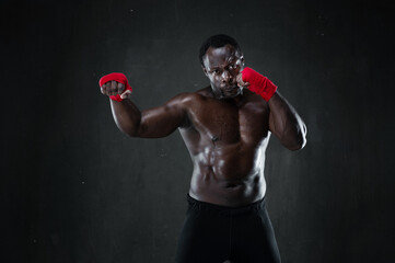 Fototapeta na wymiar Athletic boxer during boxing training. Fitness african american muscular model over black background. Strength, fighting and motion project.