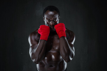 Athletic boxer in boxing protective rack. Portrait of african american male fit model over black...