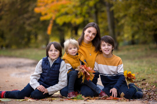Happy family, mother with children, having their autumn pictures taken in the park